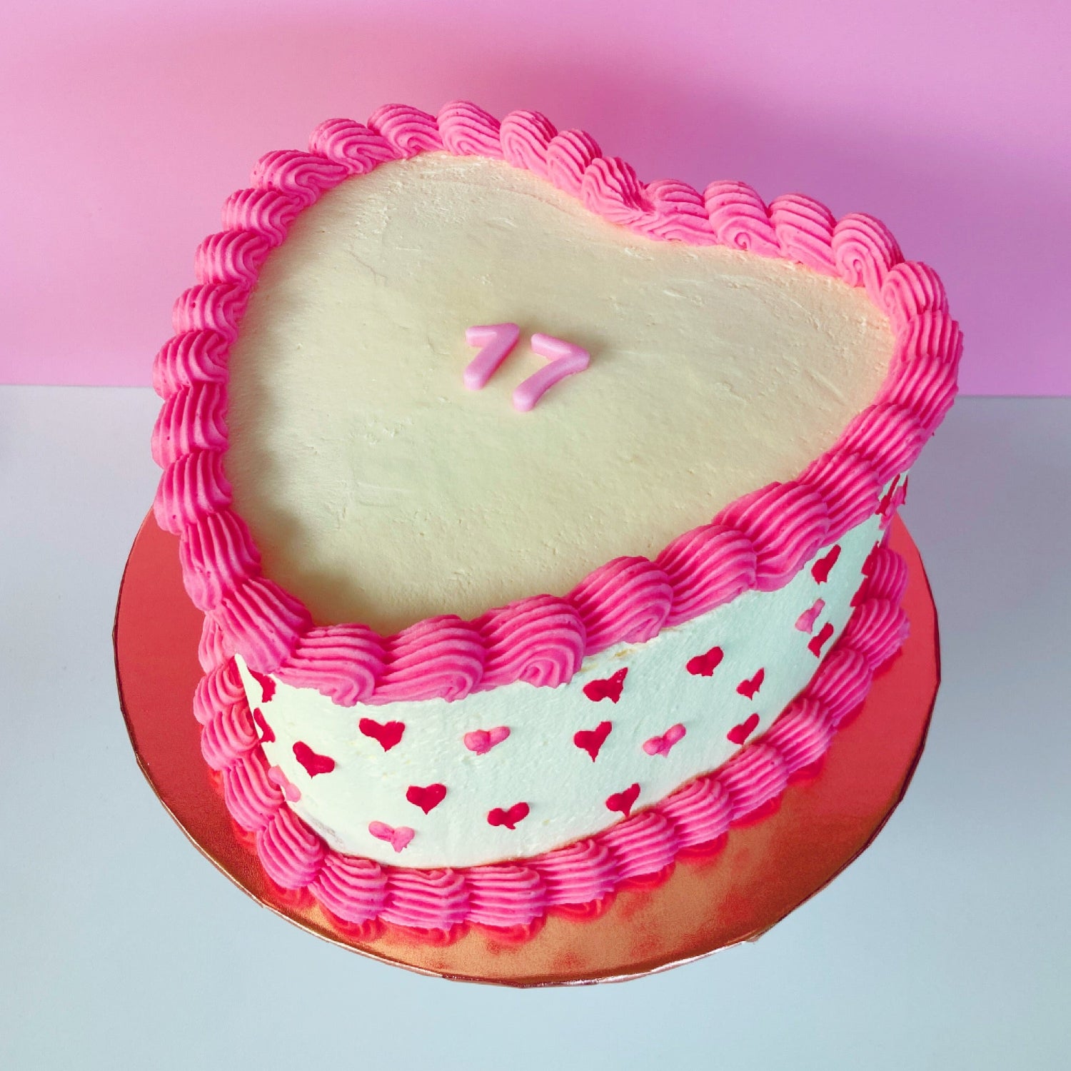 Heart-shaped 8 inch cake with pink frosting and red hearts and fondant number on top