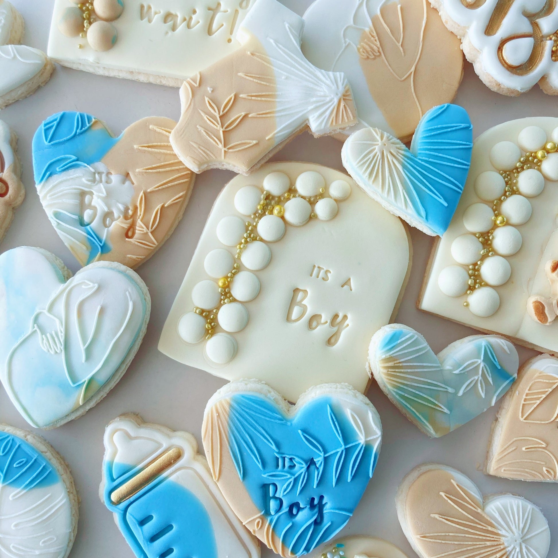 Decorative baby shower cookies with blue, white, and beige fondant