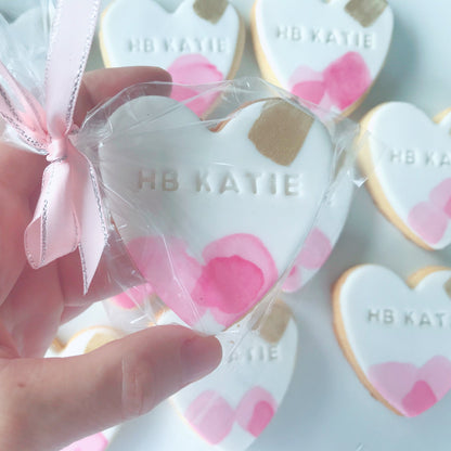 Heart-shaped cookies with 'HB Katie' branding, individually wrapped with pink ribbon.