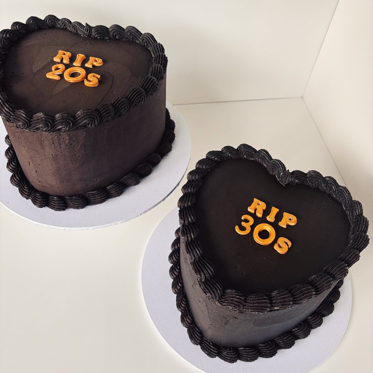 Two heart-shaped 8 inch chocolate cakes with black buttercream gold 'RIP 30s' fondant letters 