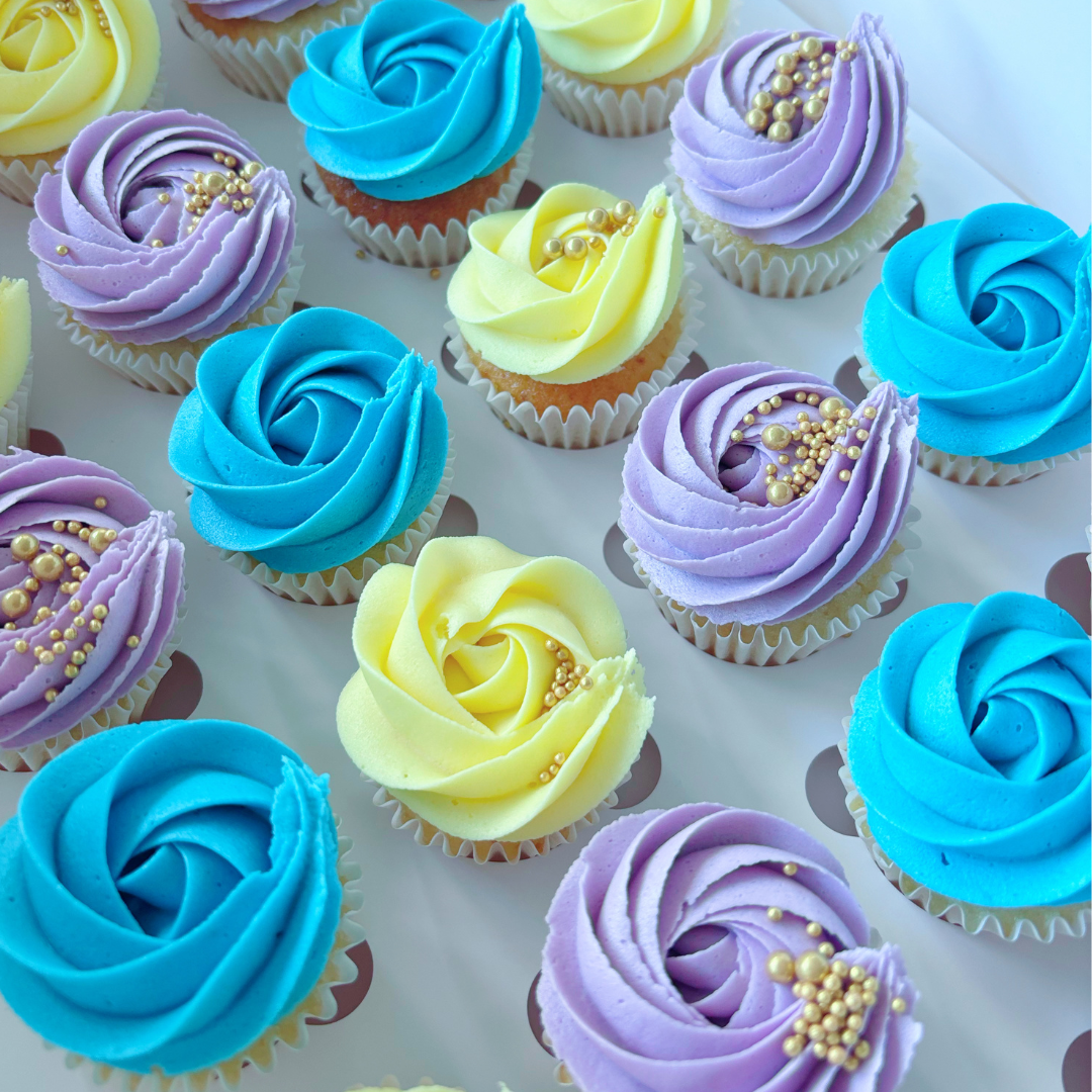 Colourful mini cupcakes with blue, yellow, and purple frosting.