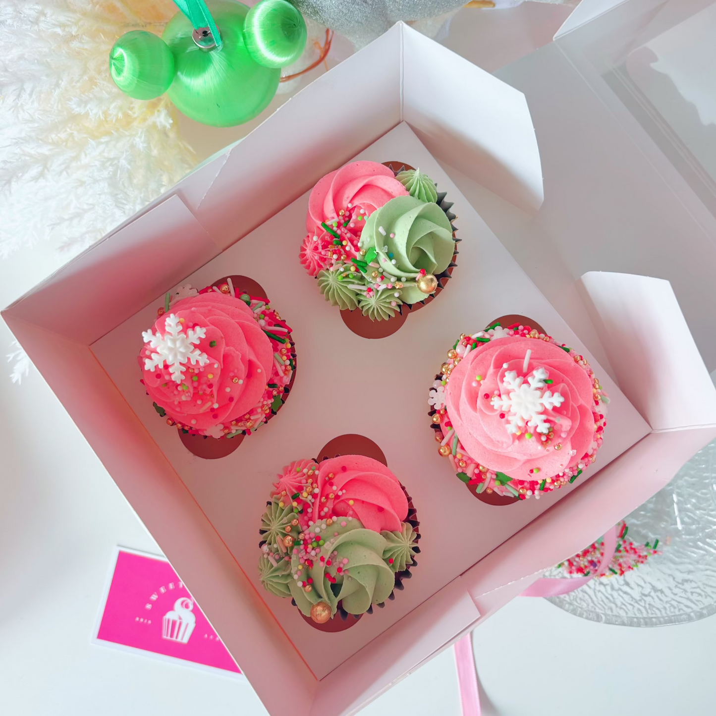 Four Christmas cupcakes with pink and green frosting.
