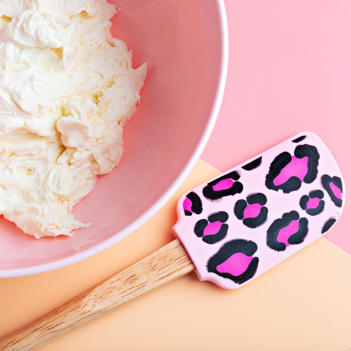 Pink bowl with American buttercream and a spatula with a leopard print & wooden handle