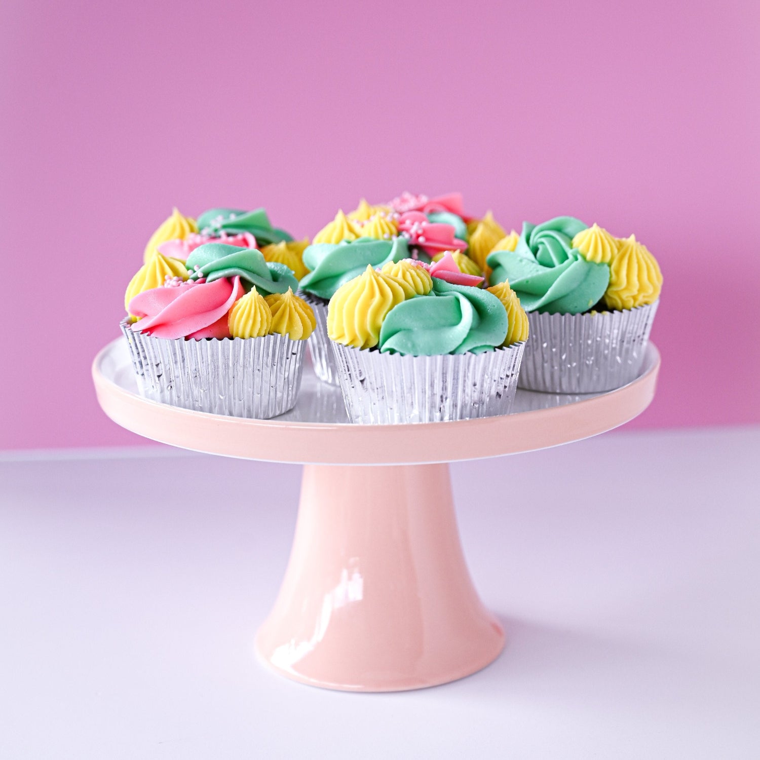 Cupcakes with colorful frosting on a pink cake stand 