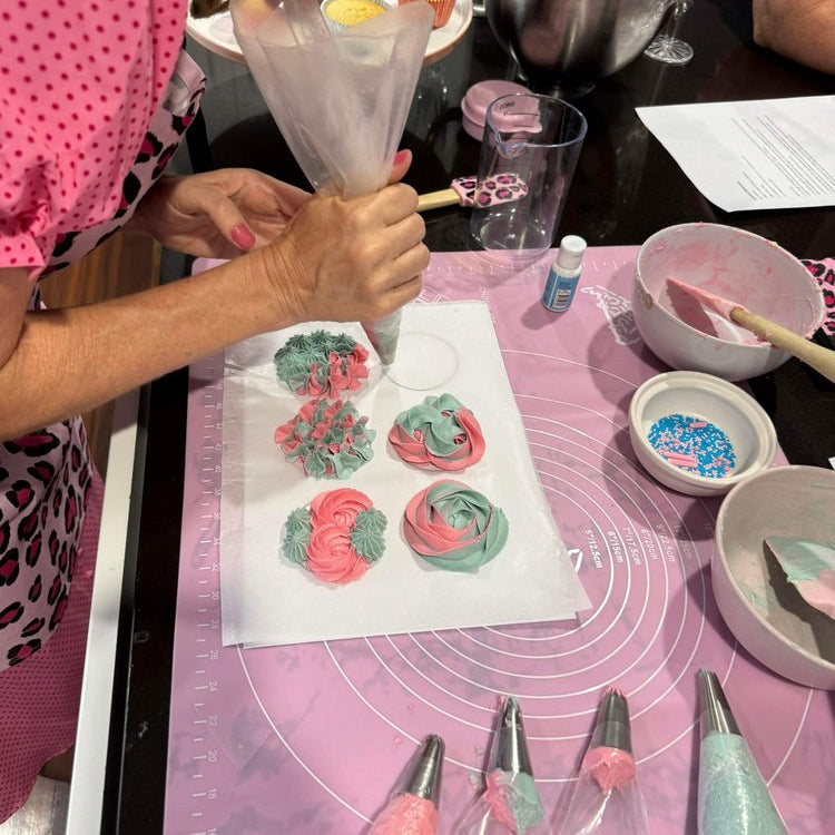 Leesa decorating cupcakes with pink and green frosting on a kitchen wiht piping tips.