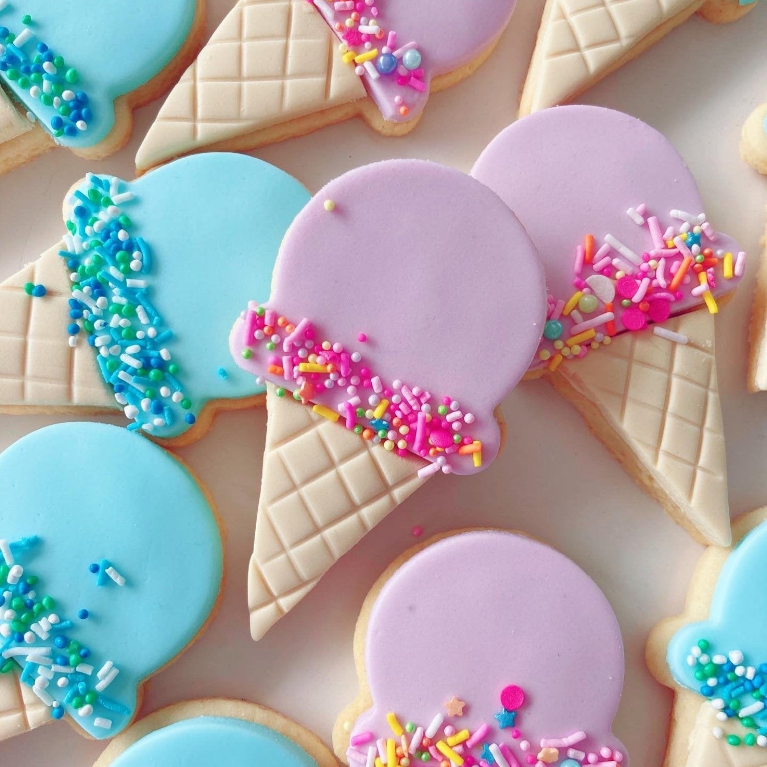 Decorative blue and pink cookies shaped like ice cream cones with colorful sprinkles.