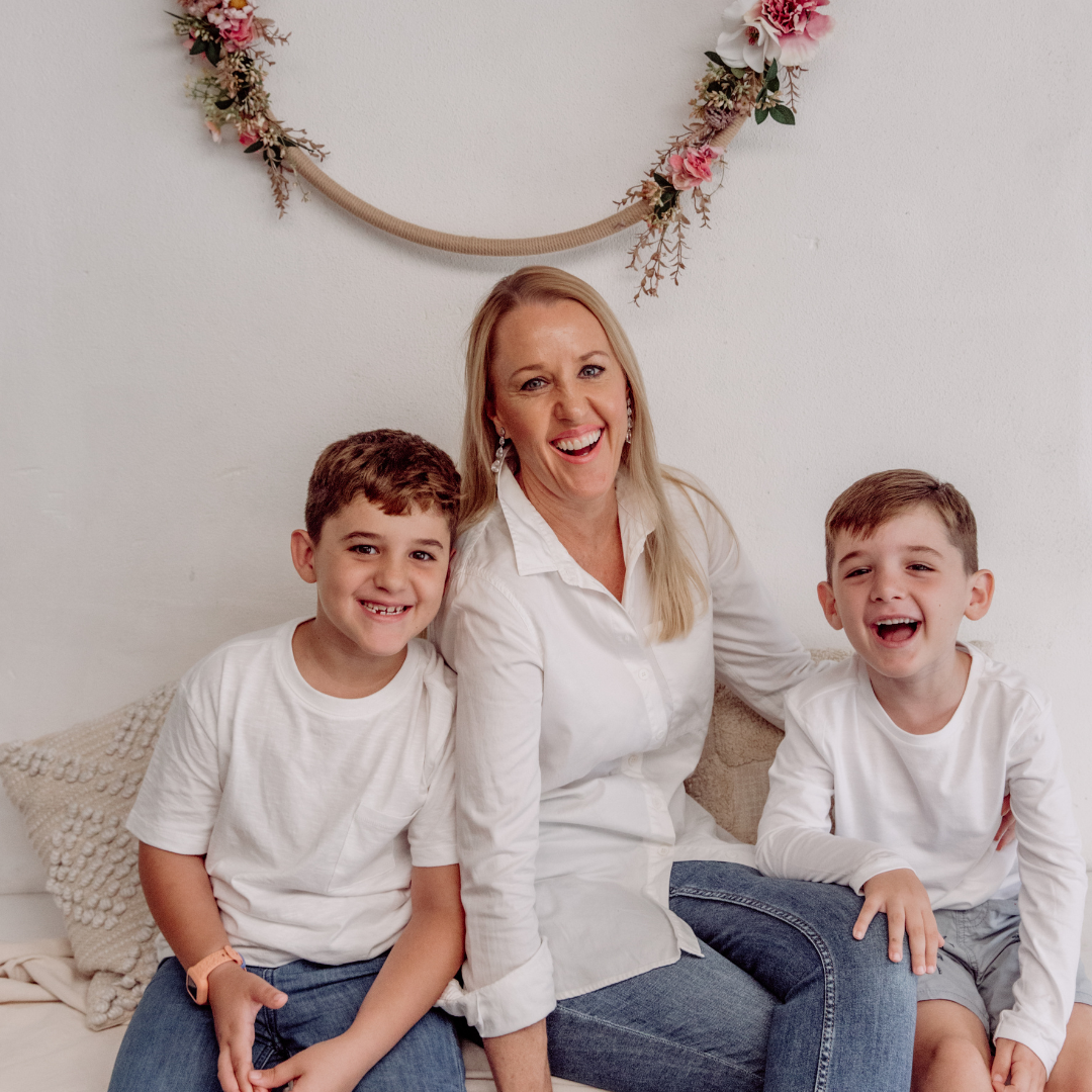 Leesa with her two children sitting on a couch in a home setting with floral decorations.