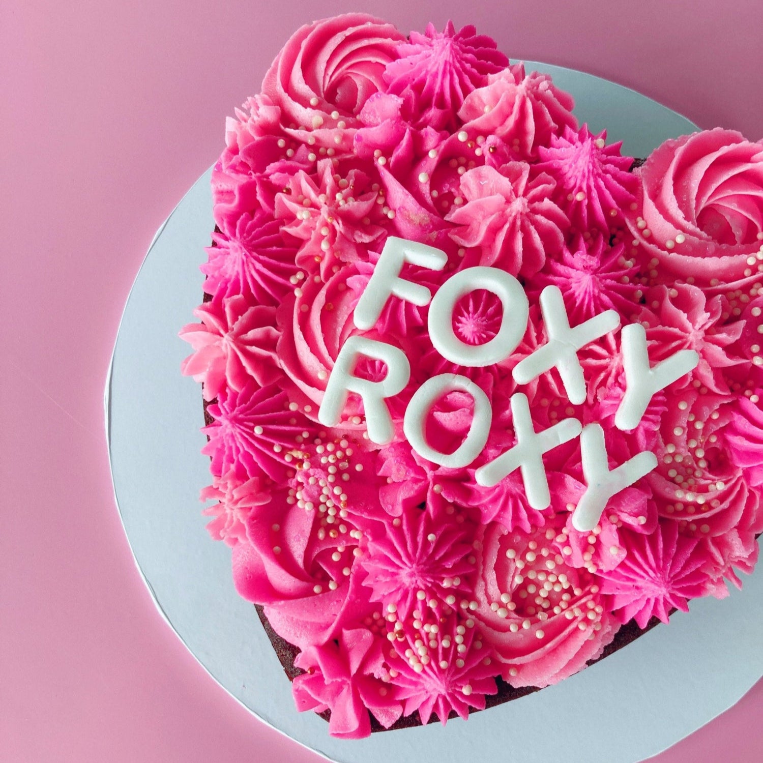 Pink frosted chocolate cake with 'FOXY ROXY' fondant letters