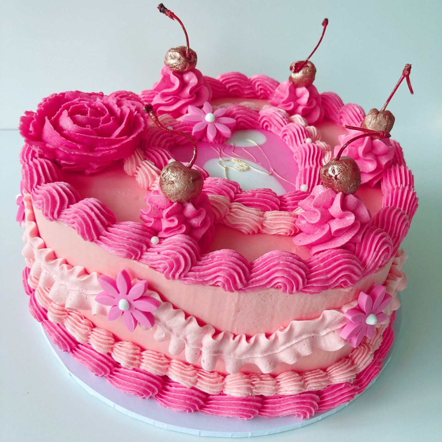 Pink heart shaped cake with floral piping and cherries 