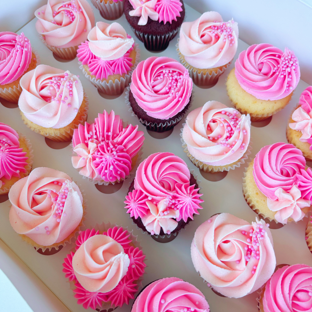 Assorted cupcakes with pink and white buttercream frosting.