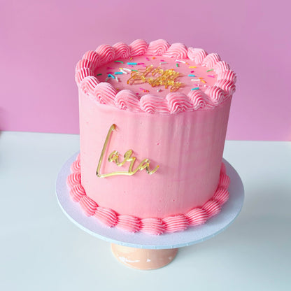 4 inch round cake with pink vintage buttercream piping and mirror gold acrylic toppers