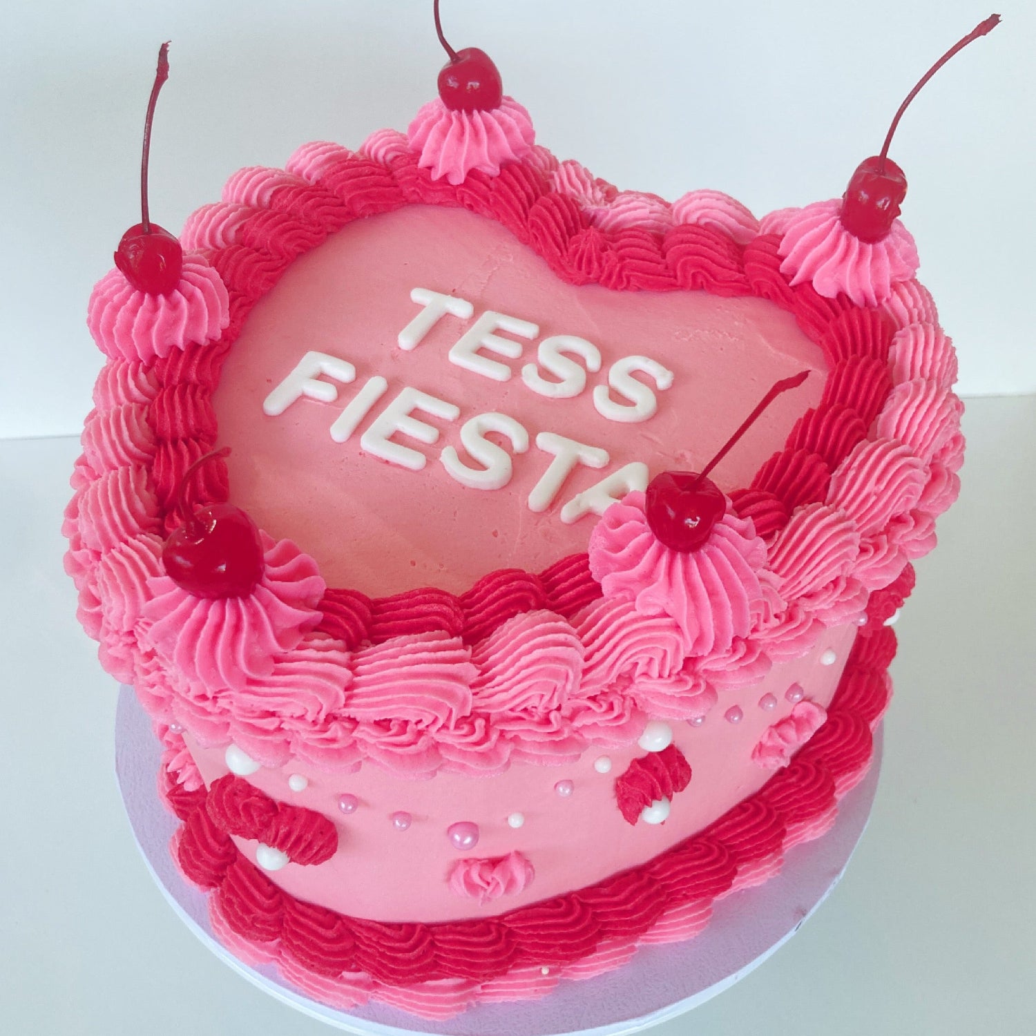 Pink 8 inch heart cake with 'Tess Fiesta' fondant letter pink buttercream piping and cherries 