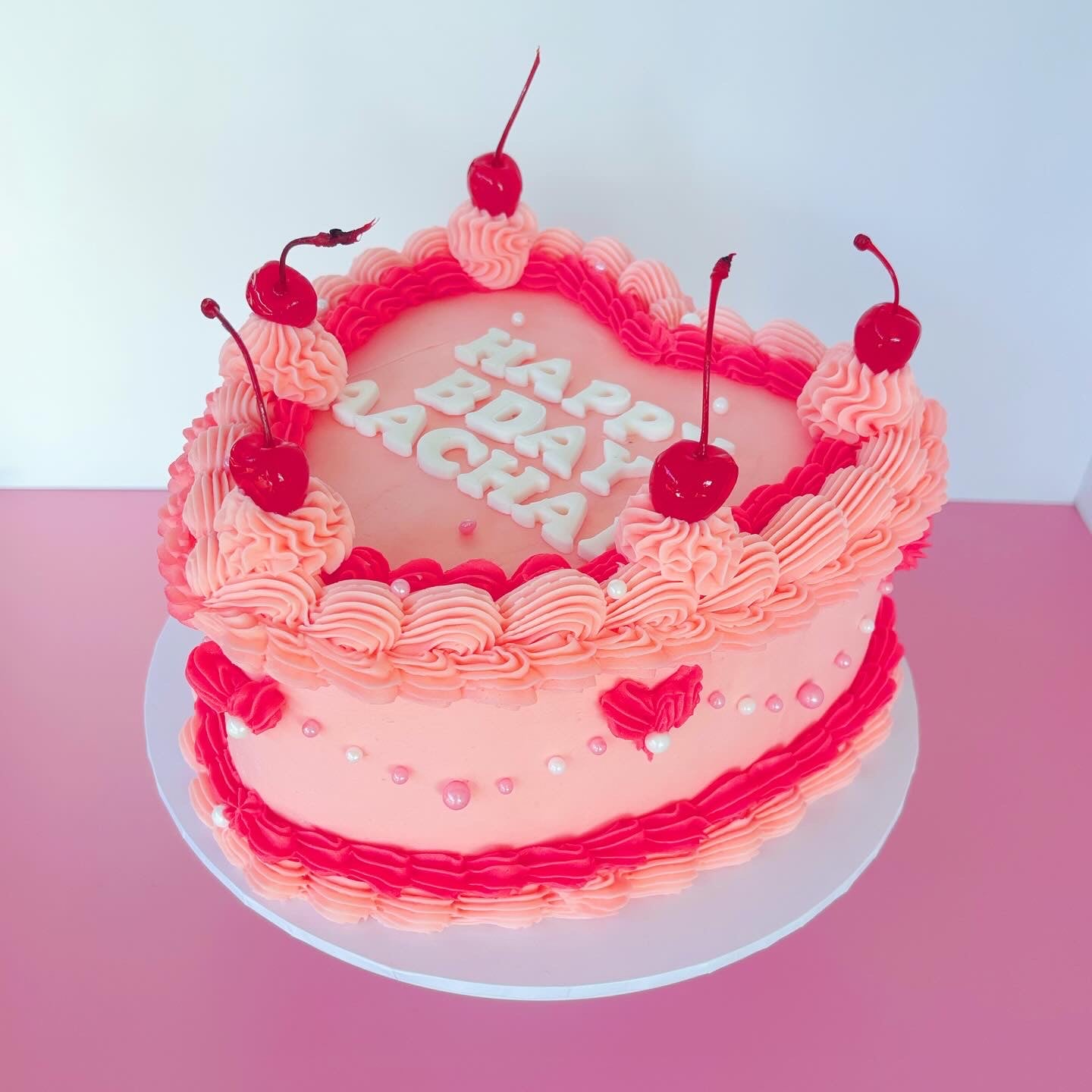 Pink 8 inch birthday cake with cherry decorations & buttercream piping