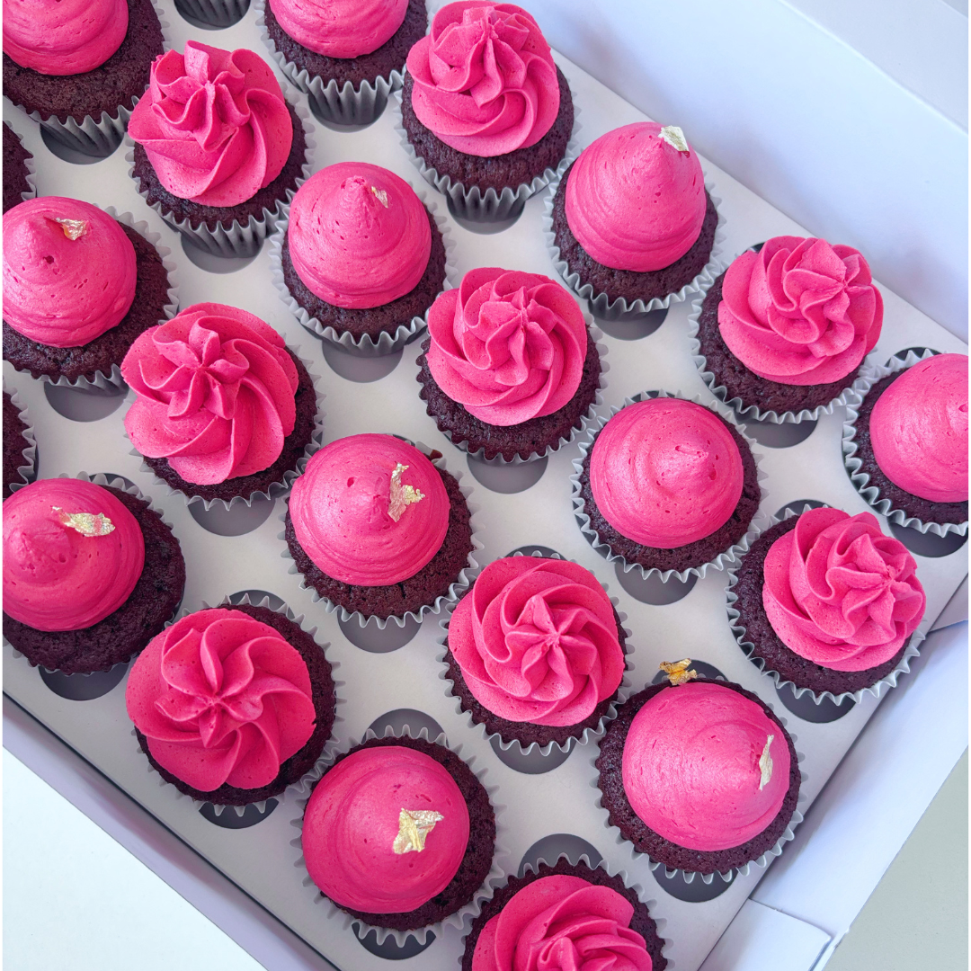 Assorted mini cupcakes with red frosting with gold leaf.