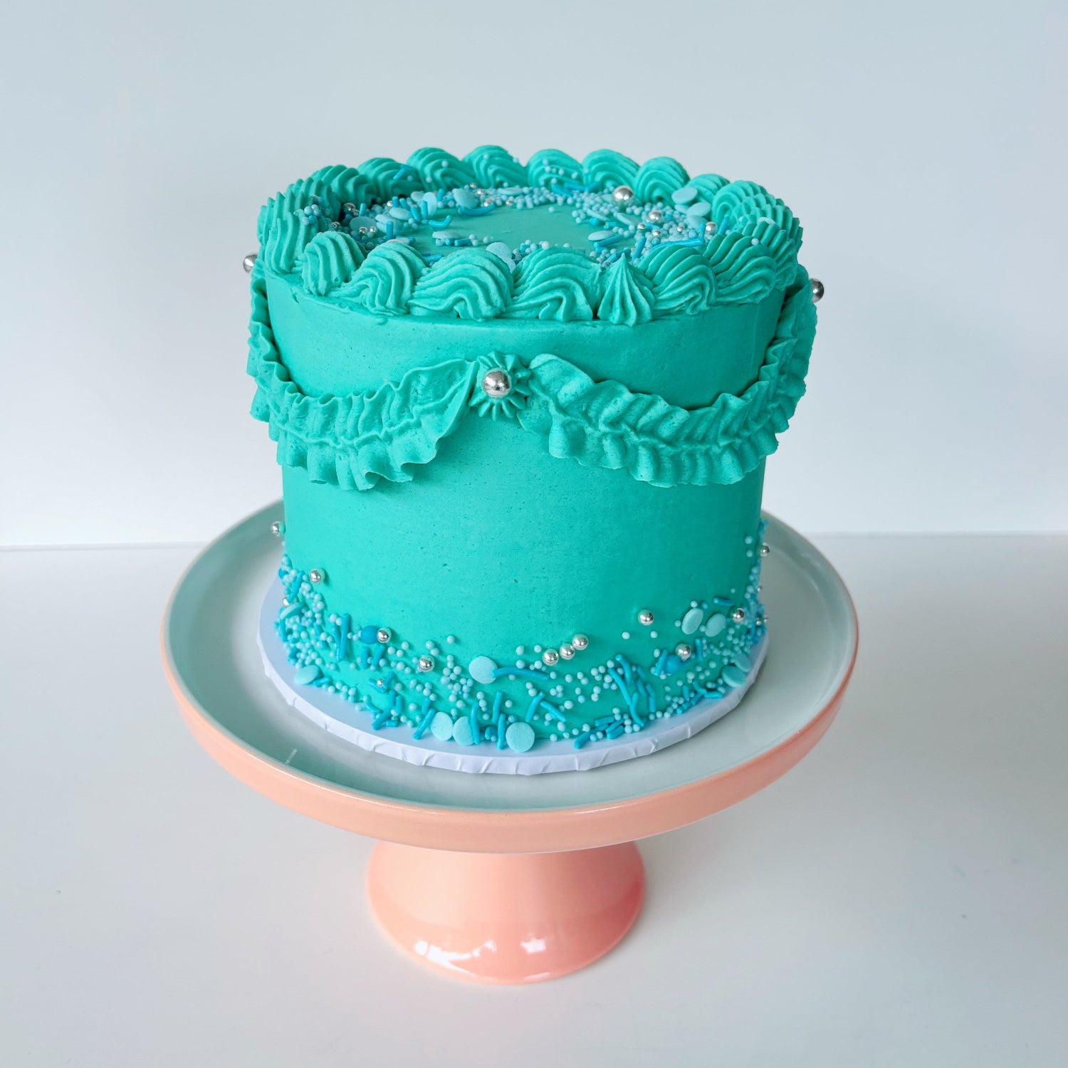 Teal 5 inch cake with decorative piping & sprinkles